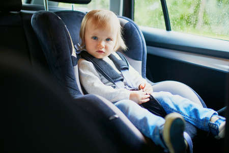 Adorable toddler girl in modern car seat. Little kid traveling by car. Child safety on the road. Trip with a babyの写真素材