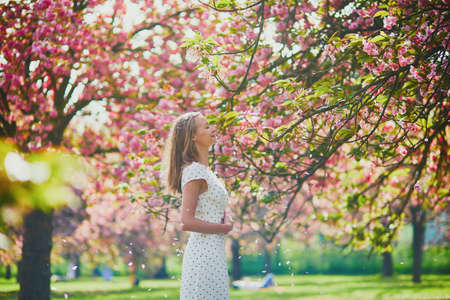 Beautiful young woman enjoying her walk in park during cherry blossom season on a nice spring dayの写真素材