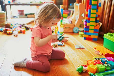 Adorable little girl drawing with green felt pen on her palm at home, in kindergaten or preschool. Stay at home entertainmentの写真素材