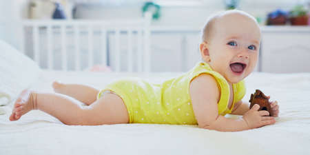 Adorable baby girl with wooden toy. Little child having fun. Infant kid in sunny nurseryの写真素材
