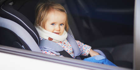Adorable toddler girl in modern car seat. Little kid traveling by car. Child safety on the road. Trip with a babyの写真素材
