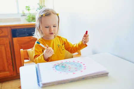 Adorable little girl drawing coronavirus with colorful aquarelle paints at home. Creative games, education and distance learning for kids. Stay at home entertainmentの写真素材