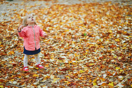 Adorable cheerful toddler girl running in Tuileries garden in Paris, France. Happy child enjoying...