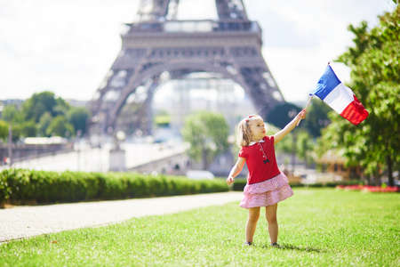 Beautiful toddler girl with French national tricolor flag near the Eiffel tower in Paris, France. 14 July (Bastille day), main French national holidayの写真素材
