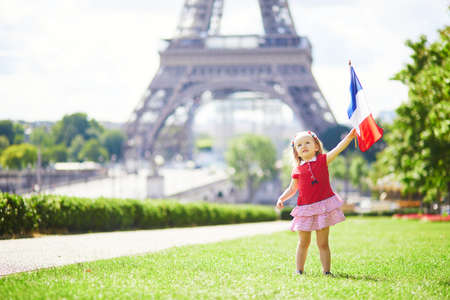 Beautiful toddler girl with French national tricolor flag near the Eiffel tower in Paris, France. 14 July (Bastille day), main French national holidayの写真素材
