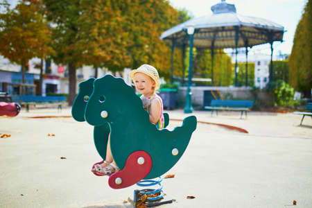 Adorable toddler girl having fun on playground. Child playing outdoors on a summer day. Outdoor activities for kidsの写真素材