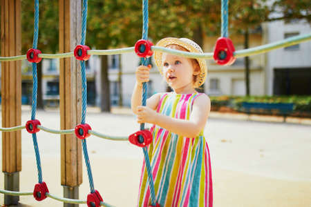 Adorable toddler girl having fun on playground. Child playing outdoors on a summer day. Outdoor activities for kidsの写真素材