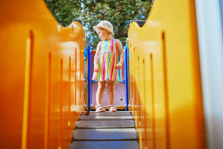 Adorable toddler girl having fun on playground. Child playing outdoors on a summer day. Outdoor activities for kidsの写真素材