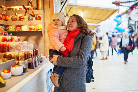 Woman and adorable toddler girl on Christmas market in Paris, France. Mother and daughter together outdoors enjoying seasonal winter holidaysの写真素材