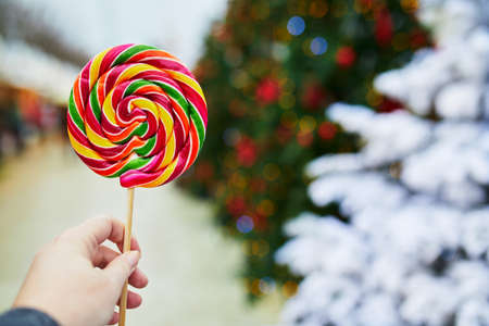 Two adorable sisters having rooster-shaped lollipops on traditional Christmas fair in Riga, Latvia. Children enjoying sweets, candies and gingerbread on Xmas market. Winter time with family and kids.の写真素材
