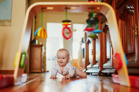 Baby girl learning to crawl. Happy healthy little child on the floor. Infant kid at homeの写真素材