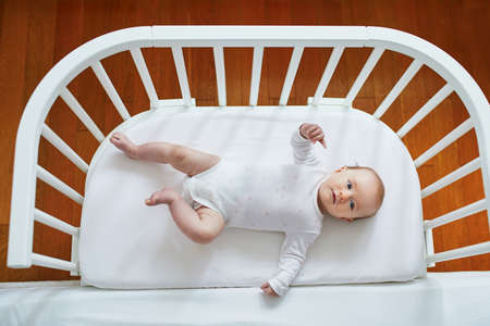 Baby girl lying in co-sleeper attached to parents' bedの写真素材