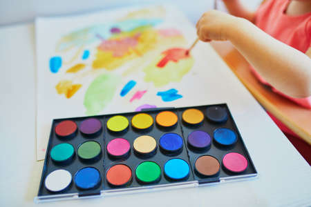 Girl drawing with colorful aquarelle paints at home, in kindergaten or preschool, closeup of palette. Creative games, education and distance learning for kids. Stay at home entertainmentの写真素材