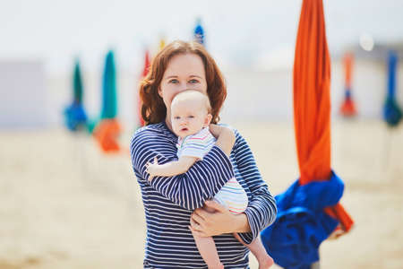 Young mother bonding with her adorable daughter. Woman and little baby girl on the beachの写真素材