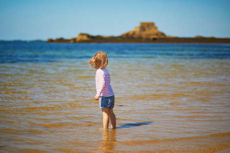 Happy toddler girl having fun on the beach in Saint-Malo, Brittany, Franceの写真素材