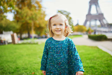 Adorable toddler girl walking near the Eiffel tower in Paris, France. Happy child enjoying fall day. Outdoor autumn activities for kidsの写真素材