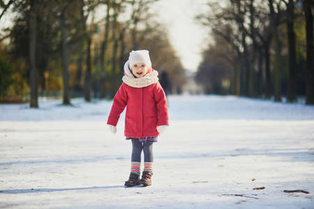 Adorable toddler girl on a sunny snow day. Happy child playing with snow. Winter activities for kidsの写真素材