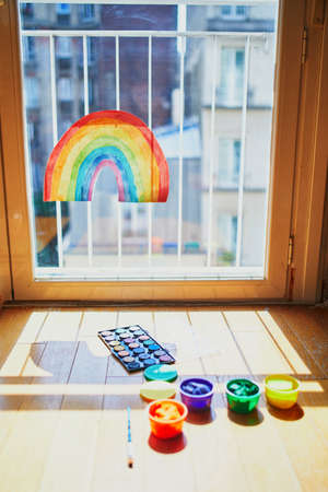 Rainbow drawing on window glass as sign of hope. Creative games for kids staying at home during lockdown. Self isolation and coronavirus quarantine conceptの写真素材