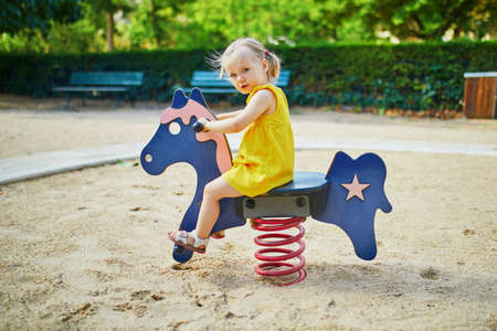 Adorable toddler girl having fun on playground. Child playing outdoors on a summer day. Outdoor activities for kidsの写真素材