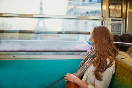 Girl travelling in a train of Parisian underground, wearing protective face mask during coronavirus outbreak. Pandemic and lockdown in France. Tourist spending vacation in France during pandemicの写真素材