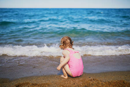 Happy little girl having fun on the beach at Mediterranean sea in France. Cheerful kid enjoying vacation at the sea. Outdoor summer activities for childrenの写真素材