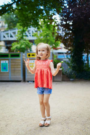 Adorable preschooler girl playing in park on a summer day. Happy child jumping. Outdoor activites...