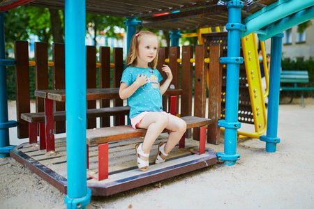 Adorable little girl on playground on a sunny day. Preschooler child playing in a small house. Outdoor activities for kidsの写真素材