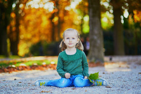 Adorable preschooler girl enjoying nice and sunny autumn day outdoors. Happy child walking in Luxembourg garden of Paris. Outdoor fall activities for kidsの写真素材