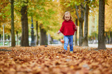 Adorable preschooler girl walking in Tuileries garden in Paris, on a fall day. Happy child enjoying autumn day. Fall season in France. Outdoor autumn activities for kidsの写真素材