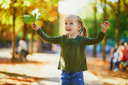 Adorable preschooler girl enjoying nice and sunny autumn day outdoors. Happy child walking in Luxembourg garden of Paris. Outdoor fall activities for kidsの写真素材