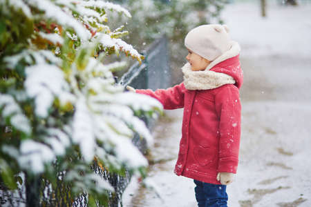 Adorable toddler girl on a day with heavy snowfall. Happy child playing with snow. Winter activities for kidsの写真素材