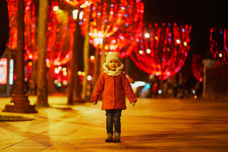 Adorable preschooler girl on Champs Elysees with its traditional Christmas illumination in Paris, France. Celebration seasonal winter holidays with kidsの写真素材