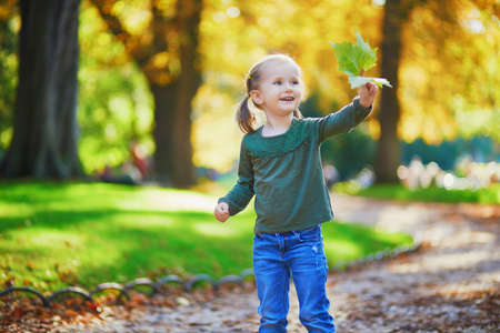 Adorable preschooler girl enjoying nice and sunny autumn day outdoors. Happy child walking in Luxembourg garden of Paris. Outdoor fall activities for kidsの写真素材