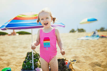 Happy little girl having fun on the beach at Mediterranean sea in France. Cheerful kid enjoying vacation at the sea. Outdoor summer activities for childrenの写真素材
