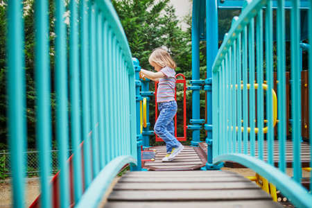 Adorable little girl on playground on a sunny day. Preschooler child playing on a slide. Outdoor activities for kidsの写真素材