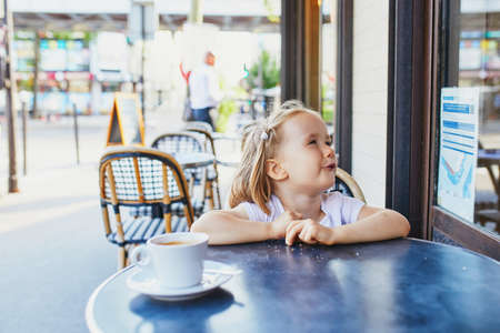 Adorable three year old girl in Parisian cafe or restaurant. Going out with kids concept