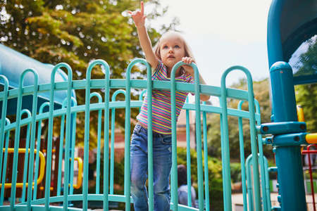 Adorable little girl on playground on a sunny day. Preschooler child playing on a slide. Outdoor activities for kidsの写真素材