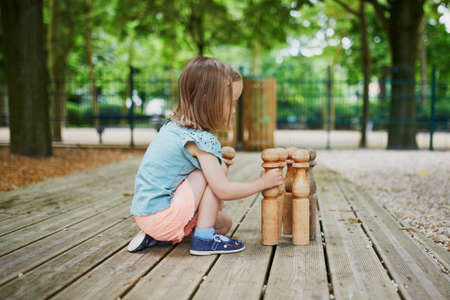 Adorable little girl on playground with bowls on a sunny day. Preschooler child playing with skittles. Outdoor activities for kidsの写真素材