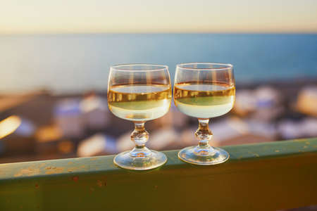 Two glasses of white wine with Atlantic coast beach in background. Normandy, Franceの写真素材