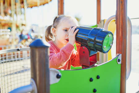 Adorable little girl on playground on a sunny day. Preschooler child playing on a slide. Outdoor activities for kidsの写真素材