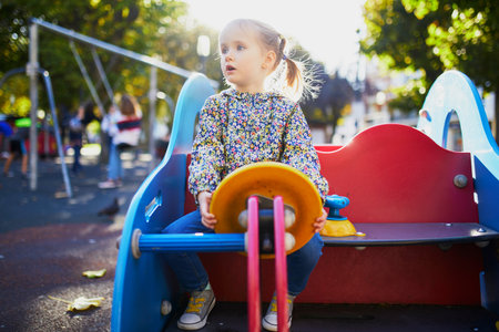 Adorable little girl on playground on a sunny day. Preschooler child playing on a slide. Outdoor activities for kidsの写真素材