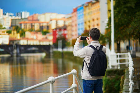 Tourist taking photo of colorful buildings on a street of Bilbao, Basque Country, Spainの写真素材