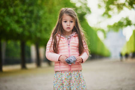 Adorable 4 year old girl with chestnuts in bloom in Tuileries garden in Paris, France. Happy kid having fun outdoorsの写真素材