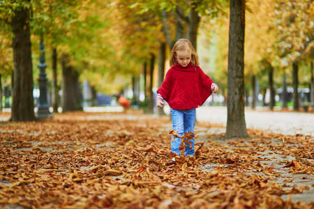 Adorable preschooler girl walking in Tuileries garden in Paris, on a fall day. Happy child enjoying autumn day. Fall season in France. Outdoor autumn activities for kidsの写真素材