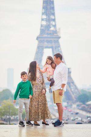 Happy family of four enjoying their trip to Paris, France. Mother, father, son and daughter near the Eiffel tower in Paris. Married couple with kids travelling in Franceの写真素材