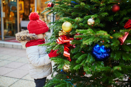 Happy cheerful preschooler girl in red hat on a Christmas market in Paris, Franceの写真素材