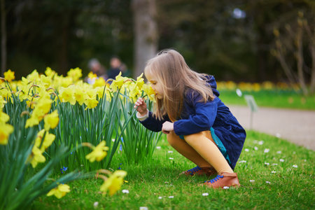 Adorable preschooler girl enjoying nice spring day in park during jonquils blooming season. Outdoor springtime activities for kids. Little child exploring natureの写真素材