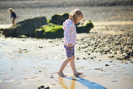Preschooler girl having fun on the sand beach at Atlantic coast of Normandy, France. Outdoor summer activities for kidsの写真素材