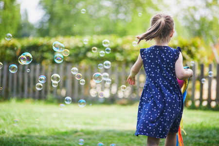 Happy cheerful preschool girl walking in park. Outdoors summer activities for kidsの写真素材