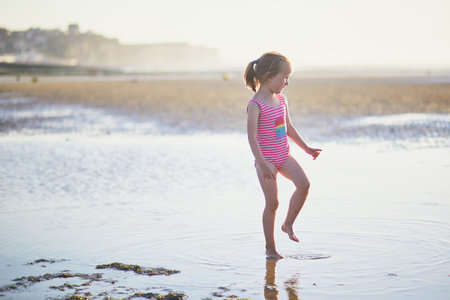 Preschooler girl having fun on the sand beach at Atlantic coast of Normandy, France. Outdoor summer activities for kidsの写真素材